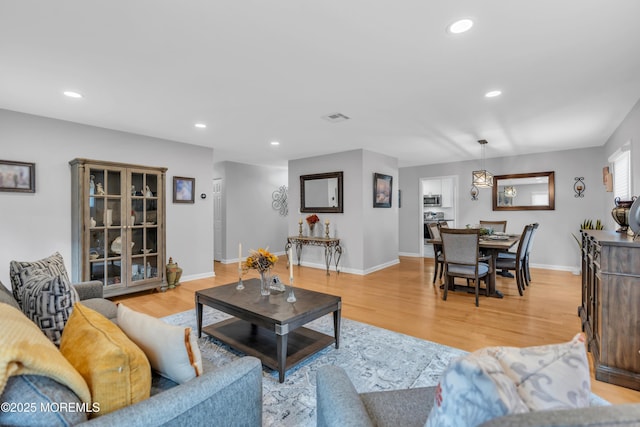 living area with baseboards, recessed lighting, and light wood-style floors