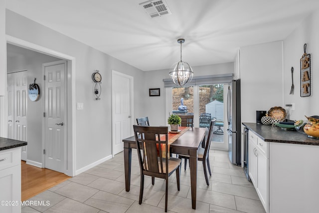 dining area featuring a chandelier, visible vents, baseboards, and light tile patterned flooring