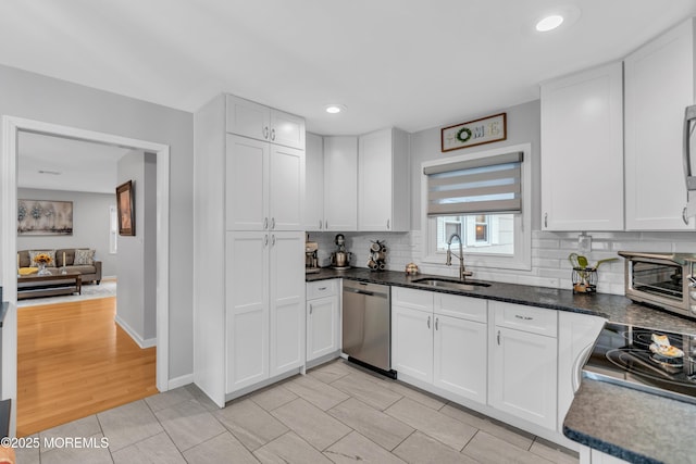 kitchen with a toaster, white cabinets, decorative backsplash, a sink, and stainless steel dishwasher