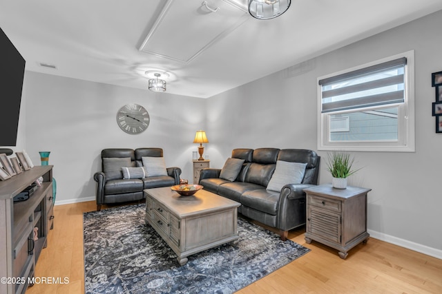 living room with attic access, light wood-style flooring, and baseboards