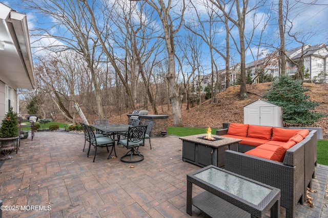 view of patio / terrace with an outdoor fire pit, outdoor dining area, an outbuilding, and a storage unit