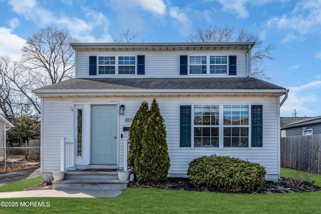 view of front of property featuring a shingled roof, fence, and a front lawn