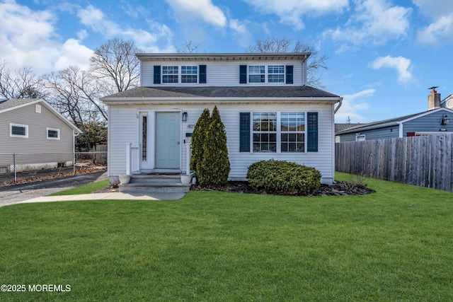 view of front of house featuring a front yard, roof with shingles, and fence