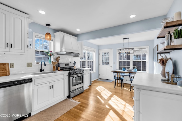 kitchen with open shelves, custom range hood, appliances with stainless steel finishes, white cabinets, and a sink