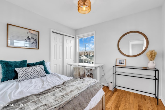 bedroom featuring light wood-style flooring, baseboards, and a closet