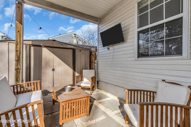 view of patio with a shed, fence, an outdoor living space, and an outbuilding