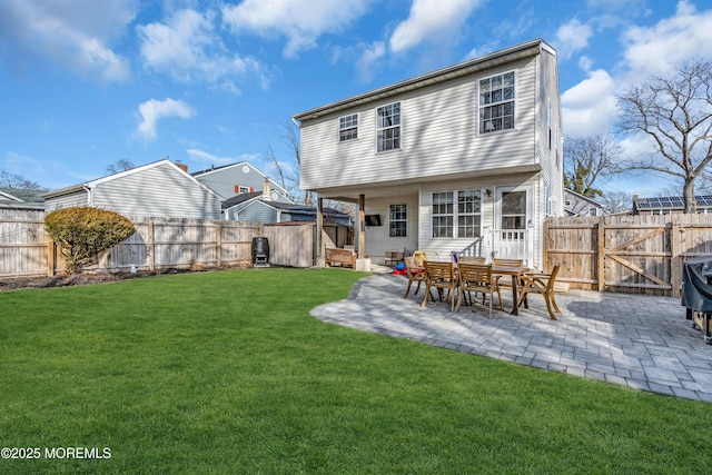 back of property with a gate, a fenced backyard, a yard, and a patio