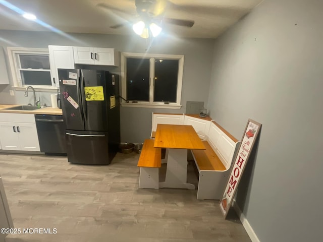 kitchen featuring light wood-type flooring, a sink, freestanding refrigerator, white cabinets, and dishwashing machine