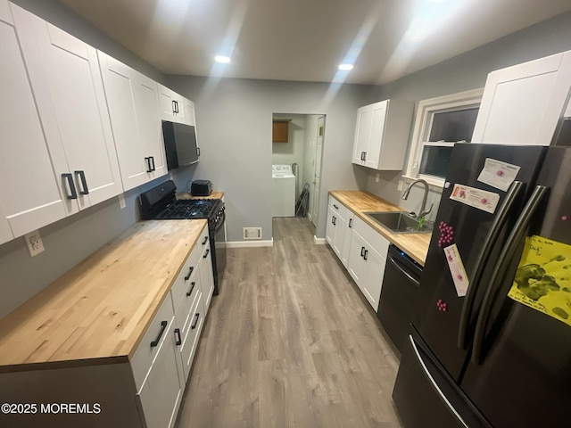 kitchen featuring a sink, black appliances, white cabinets, light wood-style floors, and butcher block counters