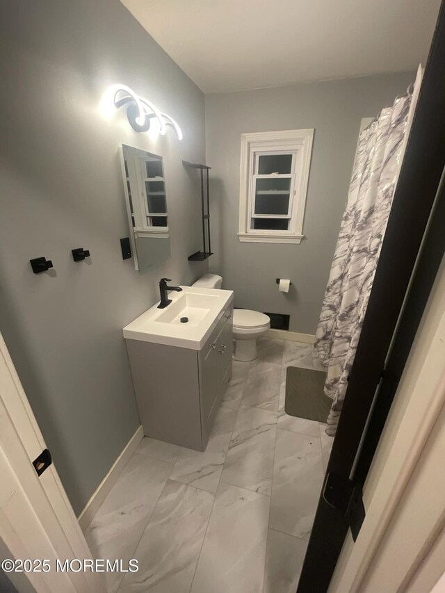 bathroom featuring vanity, toilet, baseboards, and marble finish floor