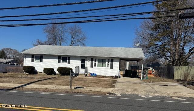 ranch-style home with an attached carport, driveway, and fence