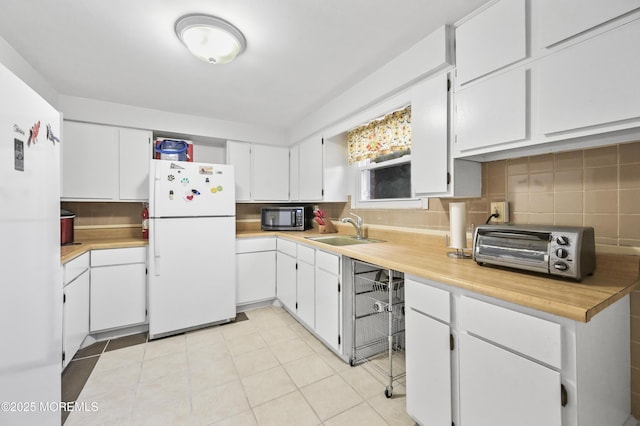 kitchen featuring freestanding refrigerator, light countertops, a sink, and backsplash