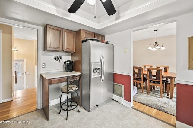 kitchen featuring a tray ceiling, decorative light fixtures, light wood-style flooring, brown cabinetry, and stainless steel fridge