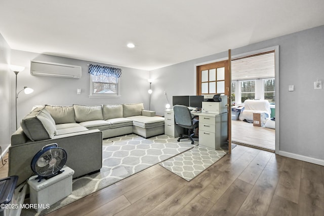 living area featuring an AC wall unit, baseboards, and wood finished floors