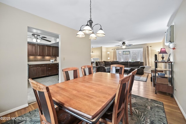 dining room featuring a wall unit AC, a baseboard heating unit, ceiling fan, light wood-type flooring, and baseboards