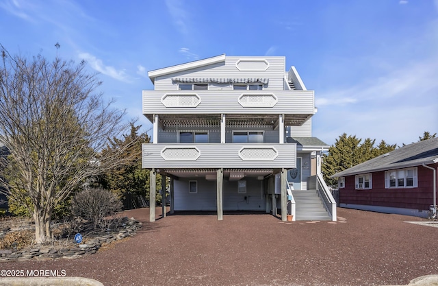 view of front of home with a carport, dirt driveway, and a balcony