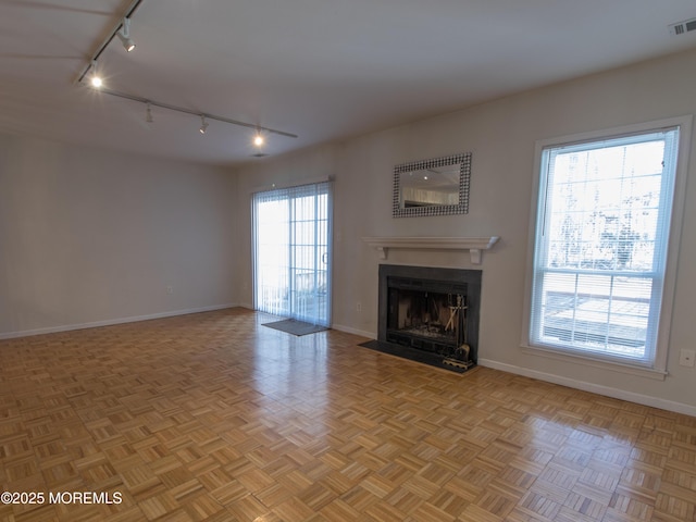 unfurnished living room with a fireplace with flush hearth, visible vents, and baseboards