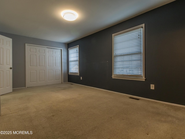 unfurnished bedroom featuring a closet, carpet, visible vents, and baseboards