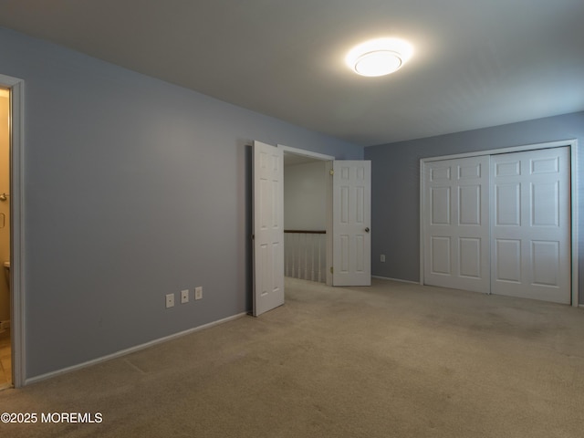 unfurnished bedroom with carpet floors, a closet, and baseboards