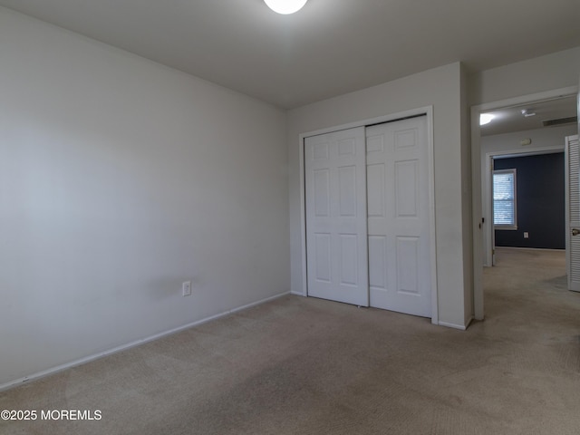 unfurnished bedroom featuring baseboards, carpet, visible vents, and a closet