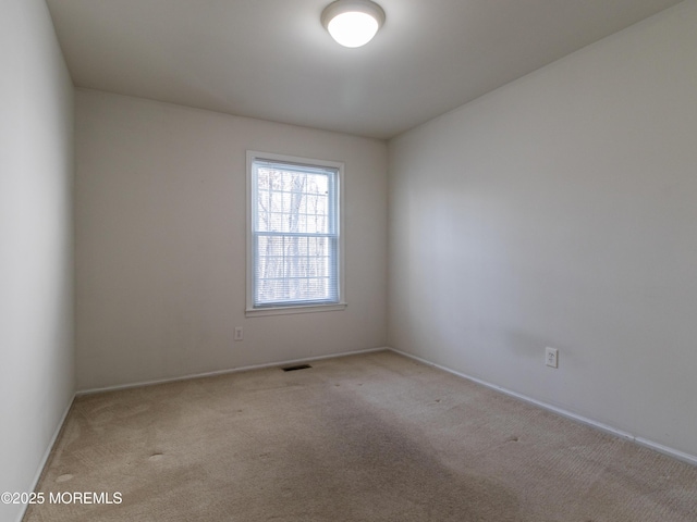 spare room with light carpet, visible vents, and baseboards