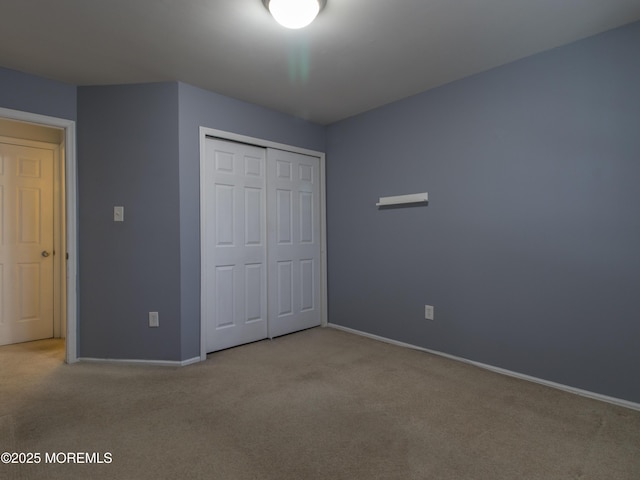 unfurnished bedroom featuring carpet, baseboards, and a closet