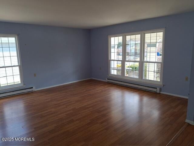 spare room with a baseboard radiator, wood finished floors, and a wealth of natural light