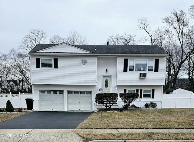 split foyer home with driveway, a garage, fence, and a front lawn