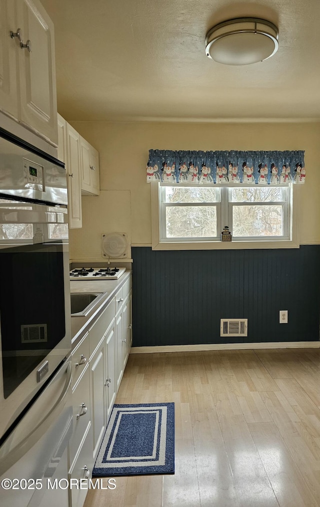 kitchen with a healthy amount of sunlight, visible vents, and white cabinets