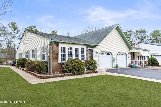 view of side of property featuring aphalt driveway, brick siding, roof with shingles, a lawn, and an attached garage