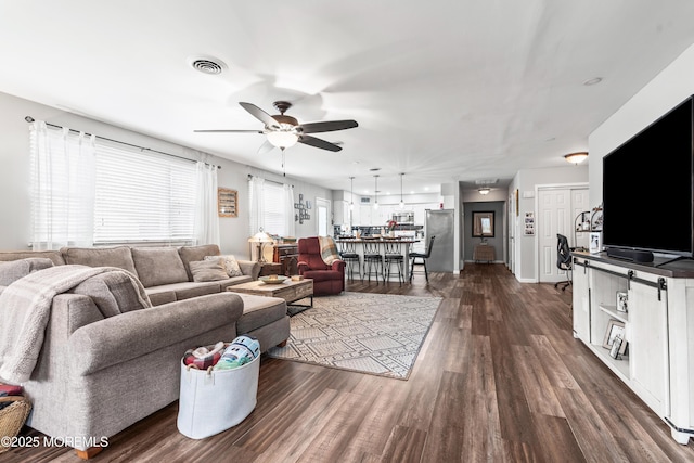 living area featuring visible vents, dark wood finished floors, and a ceiling fan