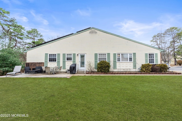 back of house featuring entry steps, a lawn, and a patio