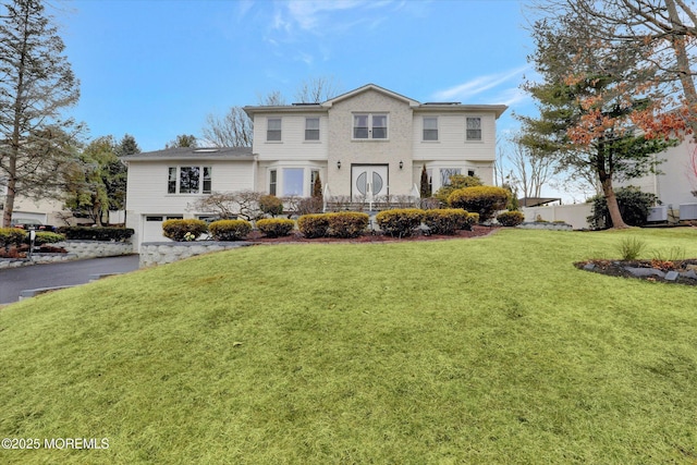 view of front of property featuring driveway, an attached garage, and a front lawn