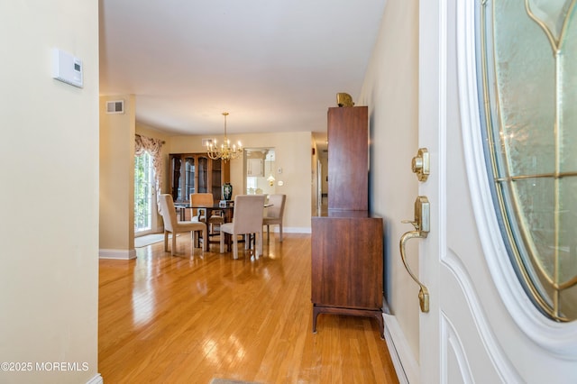 foyer entrance with a chandelier, visible vents, light wood-style flooring, and baseboards