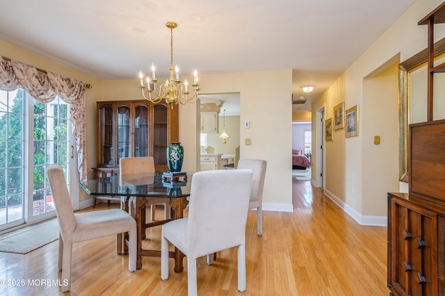 dining area featuring a chandelier, baseboards, and light wood-style floors