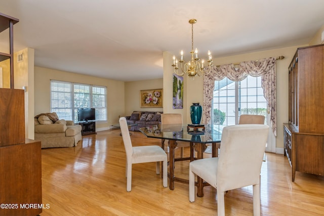 dining area with an inviting chandelier, light wood-style flooring, and baseboards