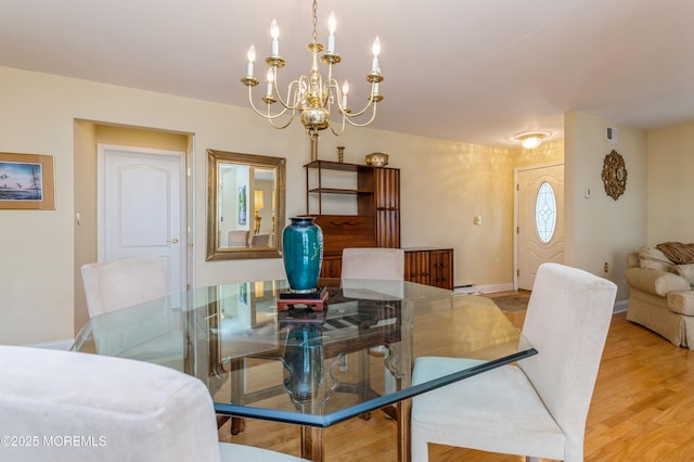 dining space featuring visible vents, baseboards, an inviting chandelier, and light wood finished floors