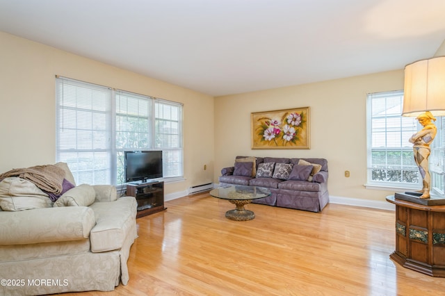 living area with a baseboard radiator, baseboards, and light wood finished floors