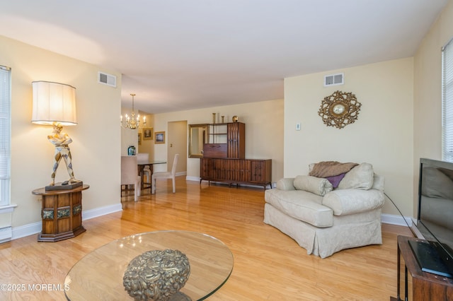 living area with a chandelier, visible vents, baseboards, and light wood-style floors