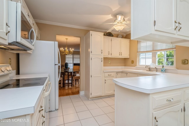 kitchen with a sink, white appliances, a peninsula, and ornamental molding