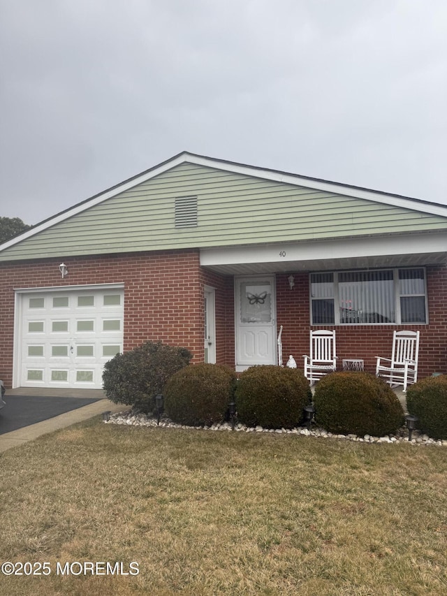 view of front facade featuring a front yard, brick siding, and an attached garage