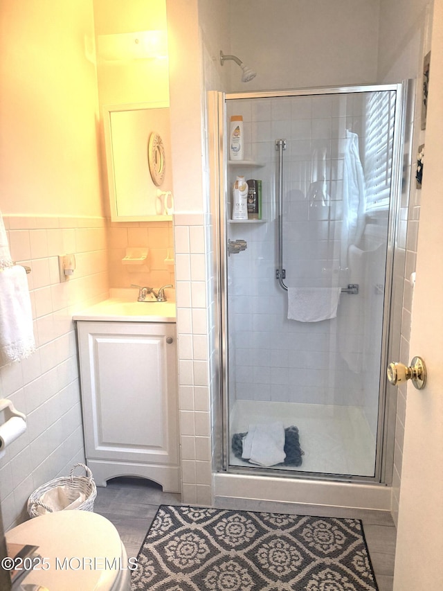 full bath with a stall shower, tile walls, toilet, and vanity