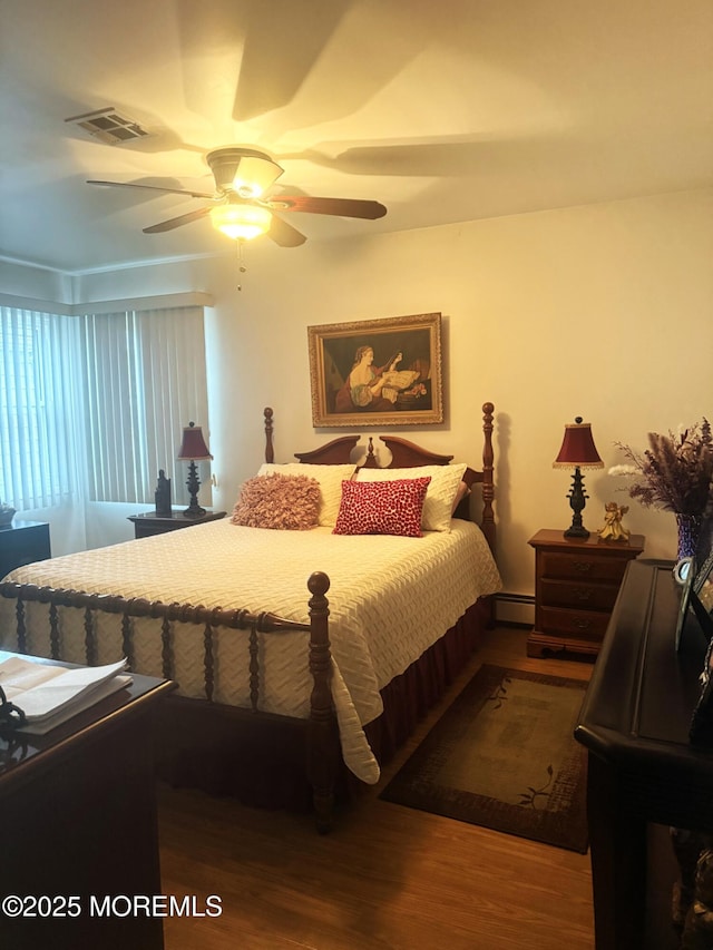 bedroom featuring visible vents, a baseboard radiator, wood finished floors, and a ceiling fan