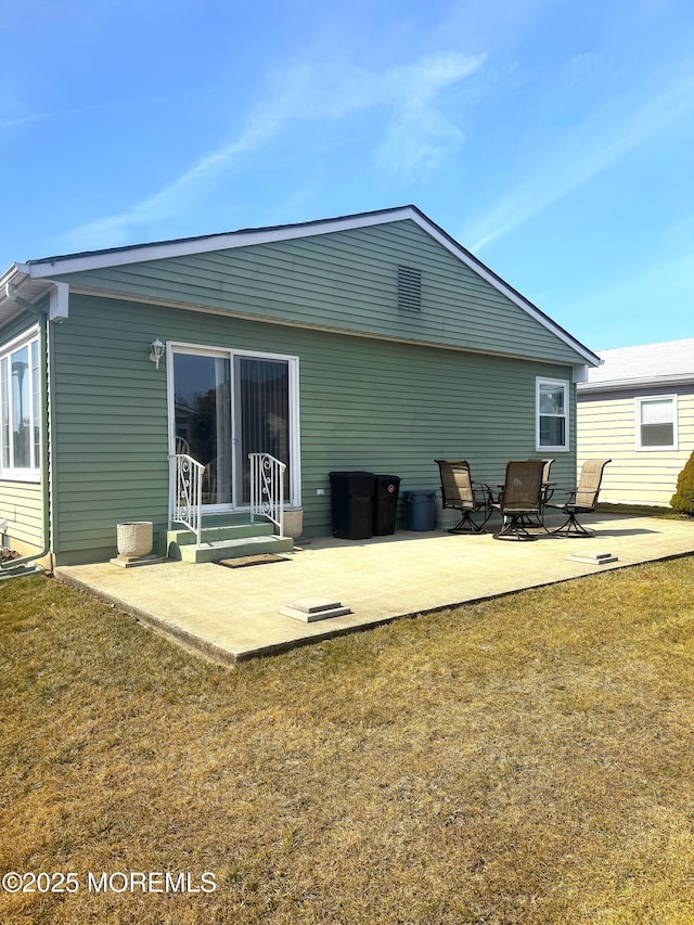 back of property with a lawn and a patio area