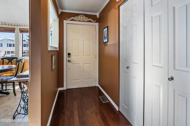 entryway with ornamental molding, visible vents, baseboards, and wood finished floors