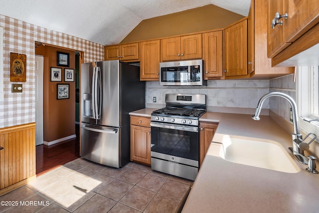 kitchen featuring stainless steel appliances, a sink, light countertops, and wallpapered walls