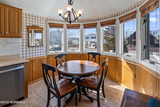 dining space with wallpapered walls, plenty of natural light, a textured ceiling, and a wainscoted wall