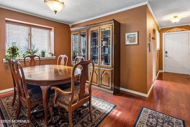 dining room featuring wood-type flooring, crown molding, a textured ceiling, and baseboards