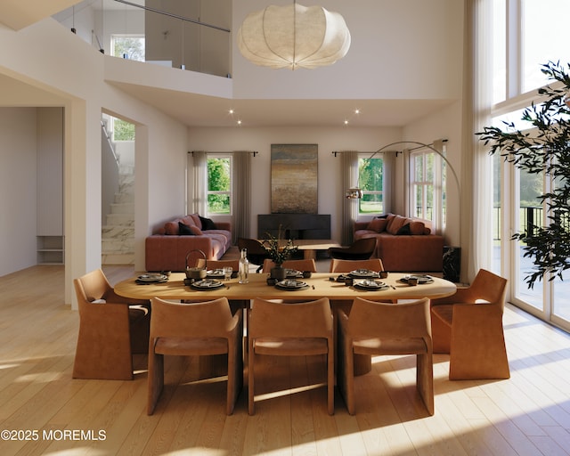 dining area featuring light wood-style flooring, a high ceiling, and stairs