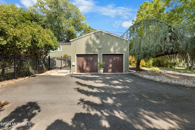 garage with aphalt driveway and fence